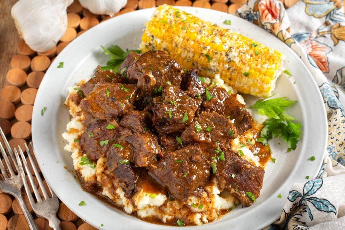 Steak Bites over mashed potatoes on plate with corn.