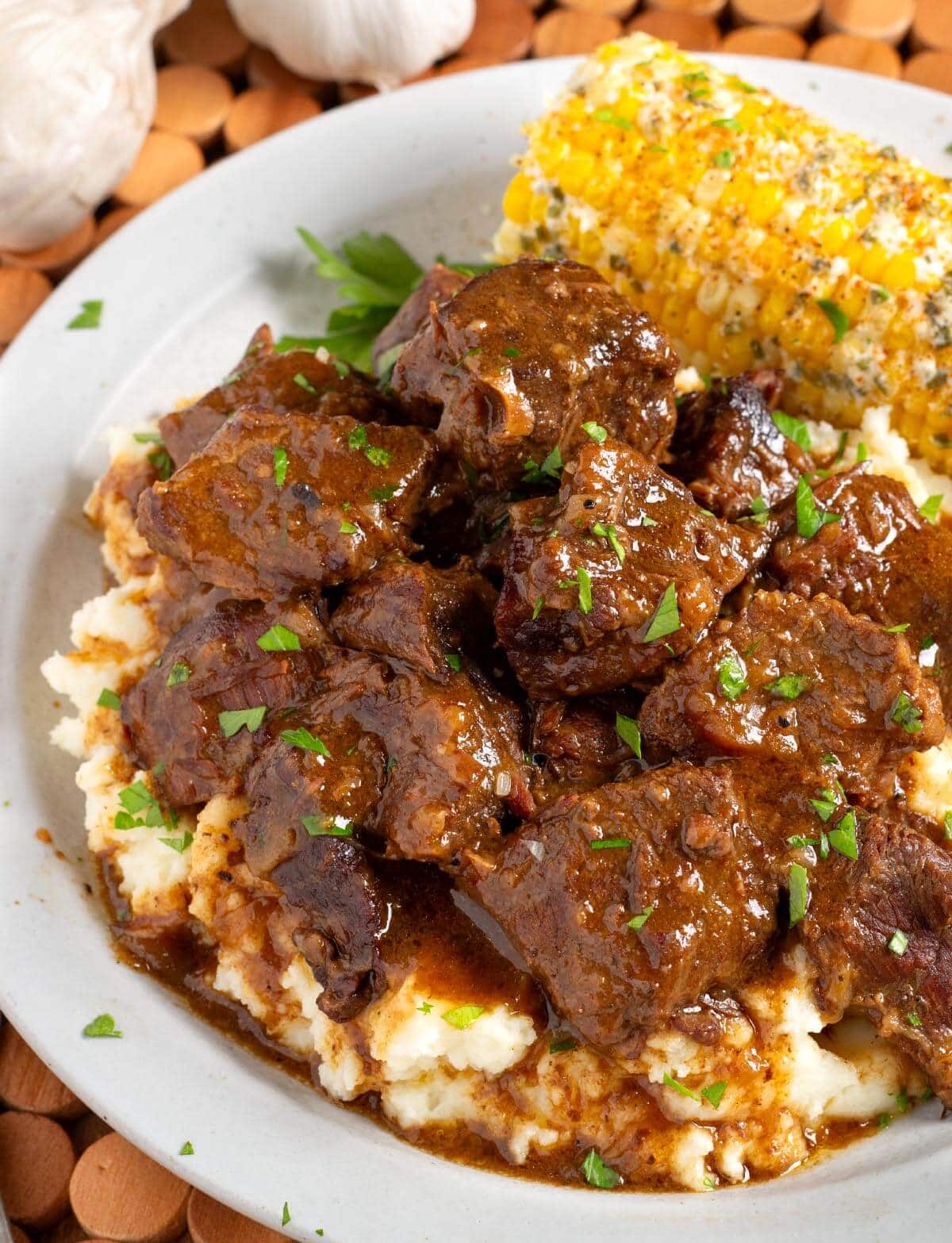 Steak Bites over mashed potatoes on plate with corn.