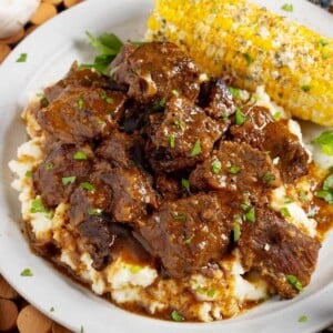 Steak Bites over mashed potatoes on plate with corn.