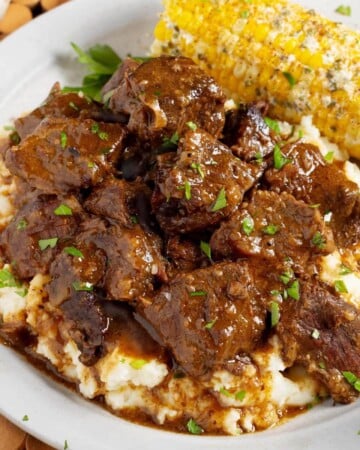 Steak Bites over mashed potatoes on plate with corn.