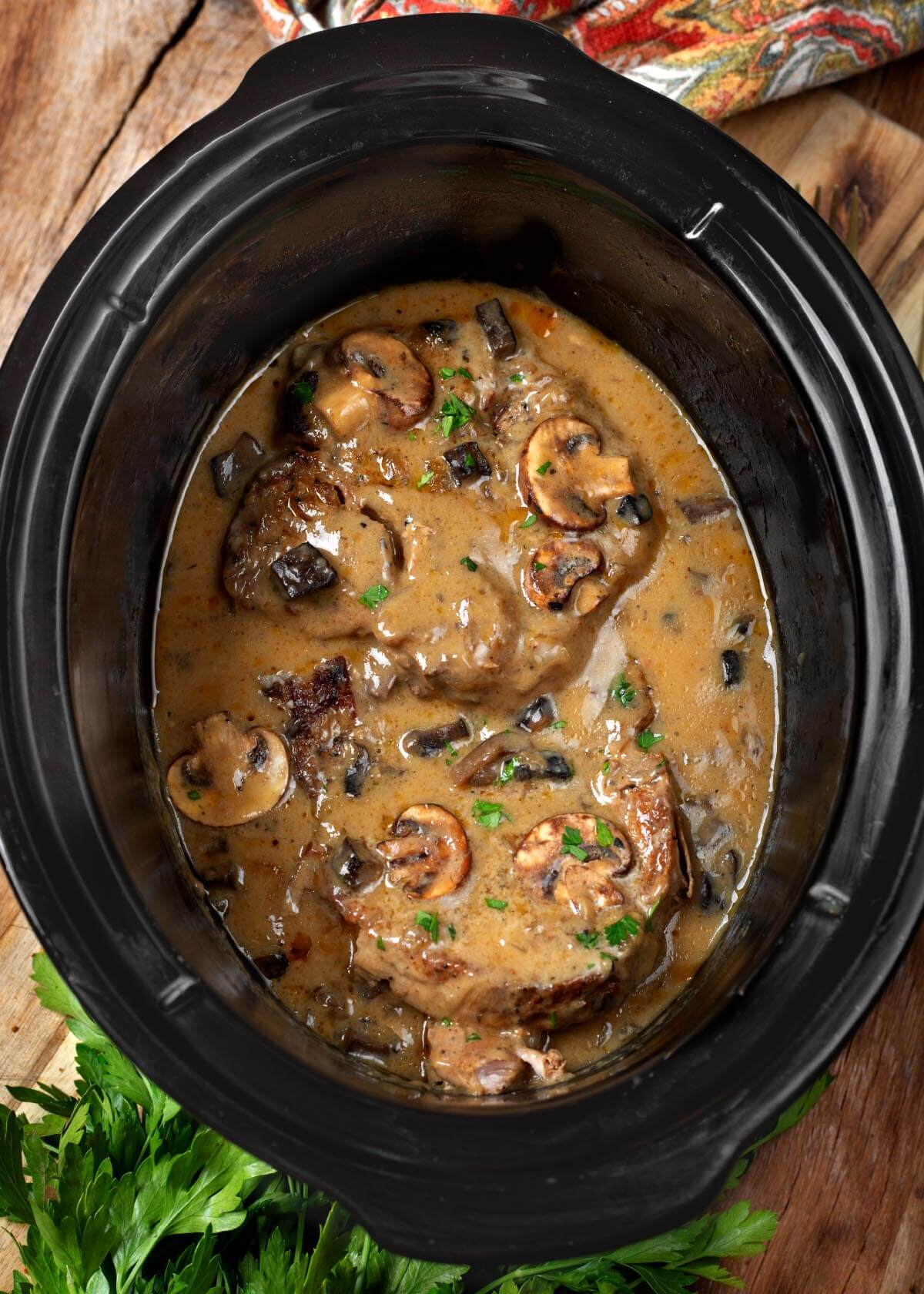 Slow Cooker Pork Chops with Mushroom Gravy in a black crock