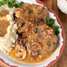 Slow Cooker Pork Chops with Mushroom Gravy and mashed potatoes on a plate.