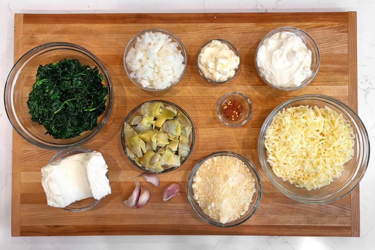 Slow Cooker Spinach Artichoke Dip ingredients shot on a board.