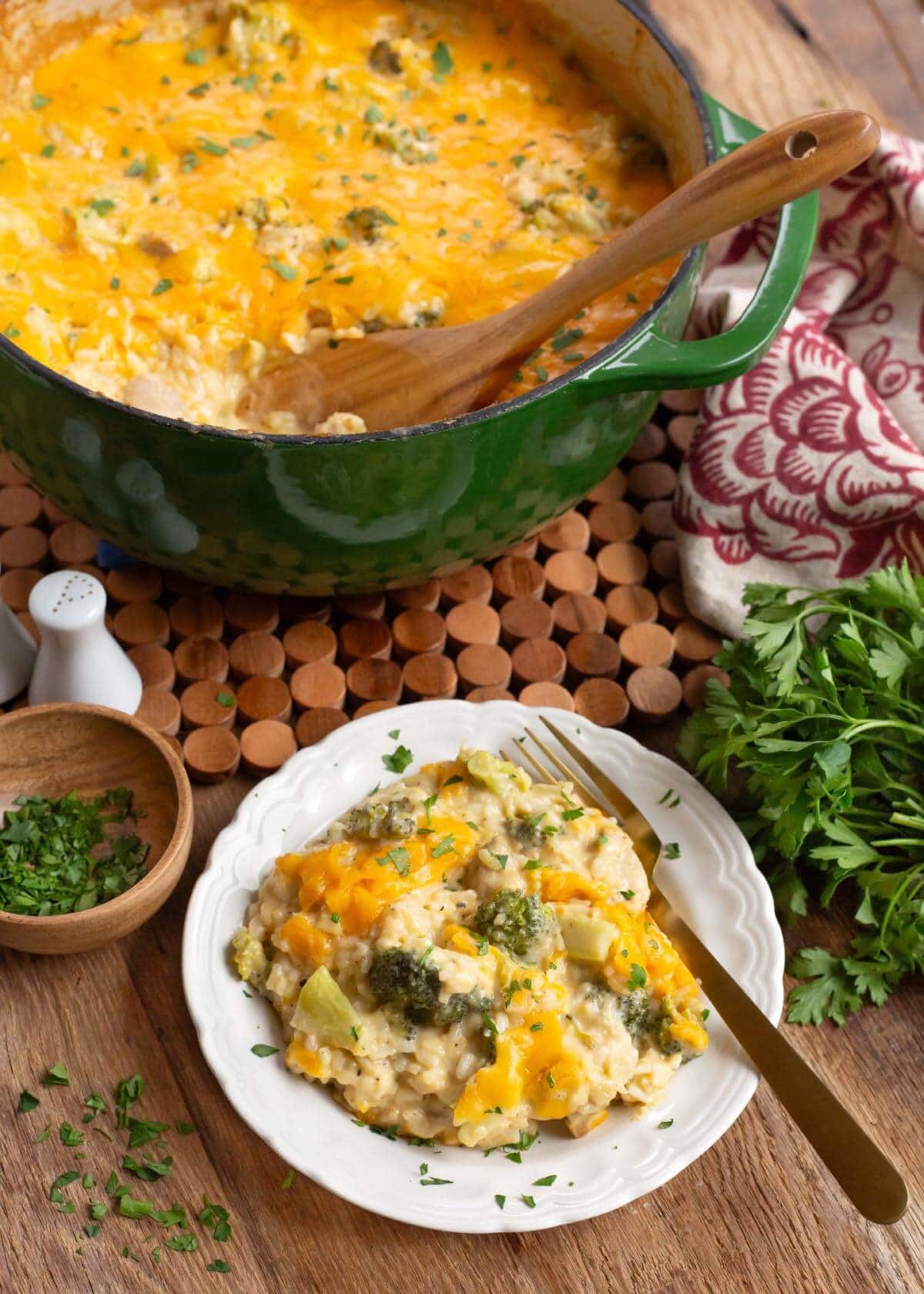 Cheesy Chicken Broccoli Rice Casserole on white plate with green pot in back.