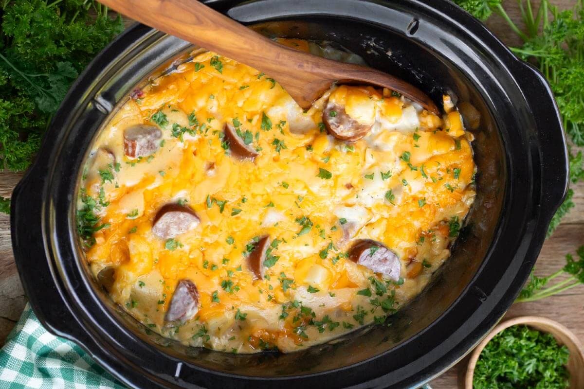 Crockpot Cheesy Potatoes with Kielbasa in a black crock