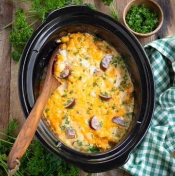 Crockpot Cheesy Potatoes with Kielbasa in a black crock