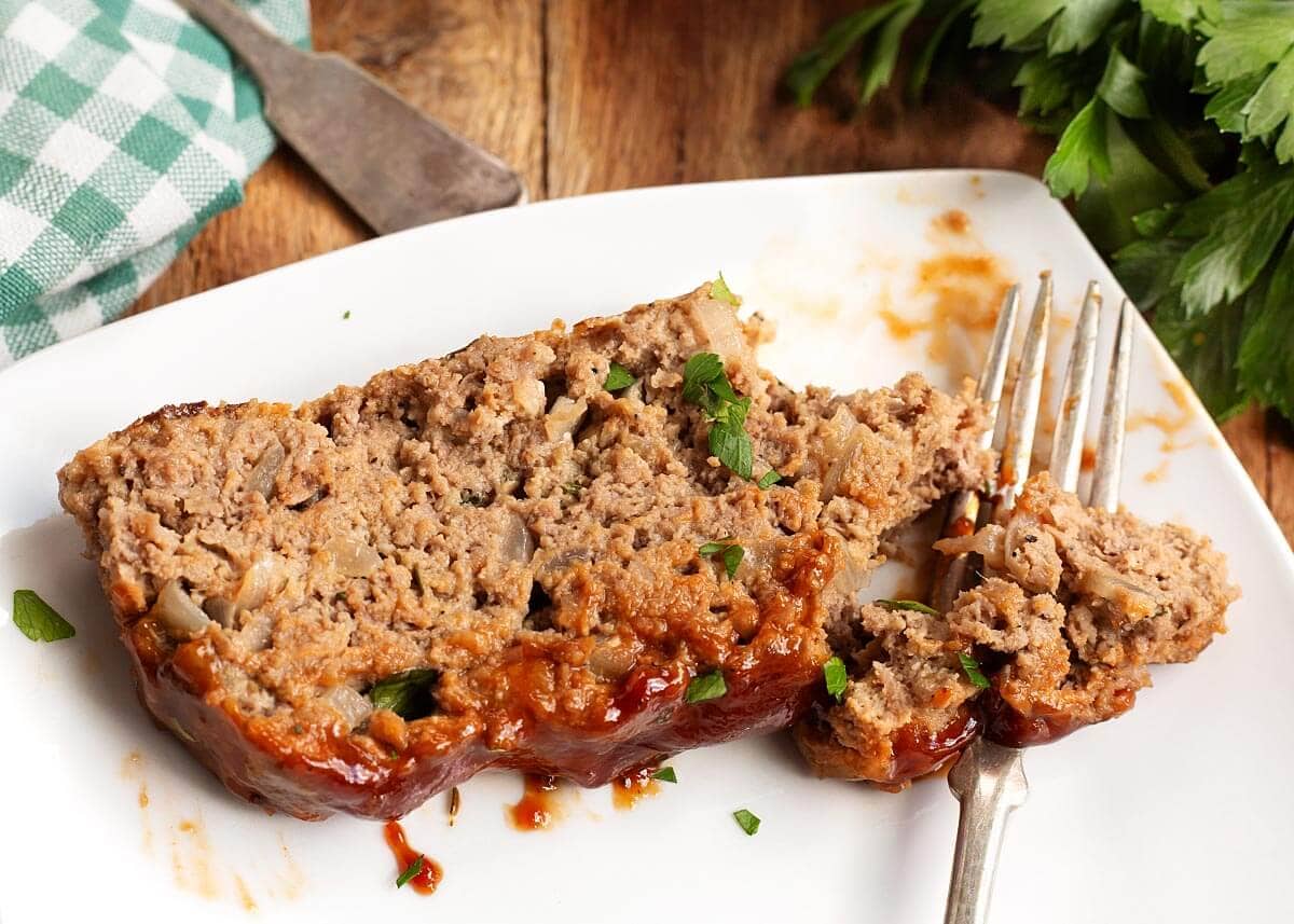 slice of meatloaf on a white plate with a fork
