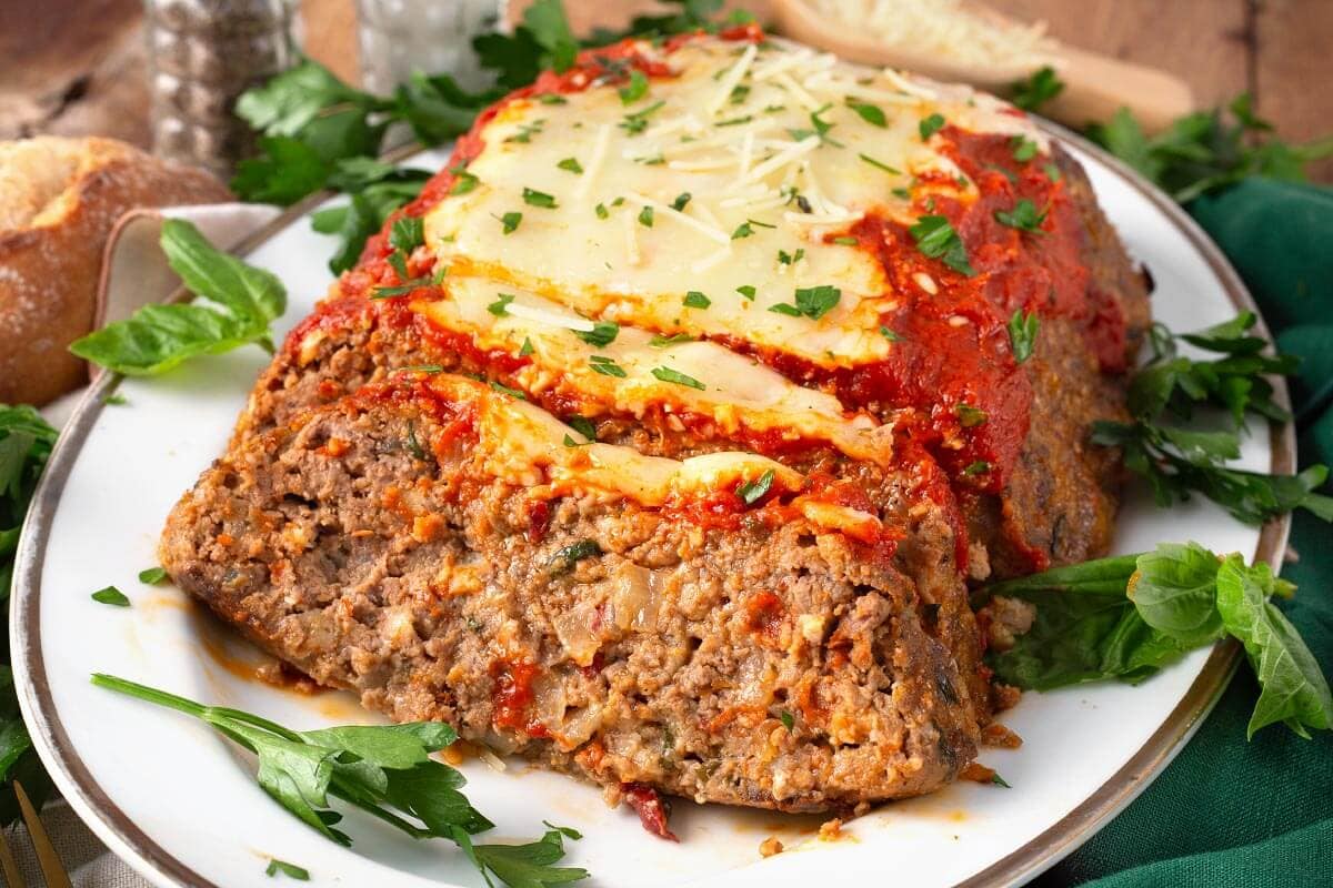 italian meatloaf partially sliced on a white platter
