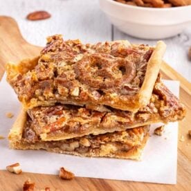 3 pieces of pecan slab pie on a wood board with parchment