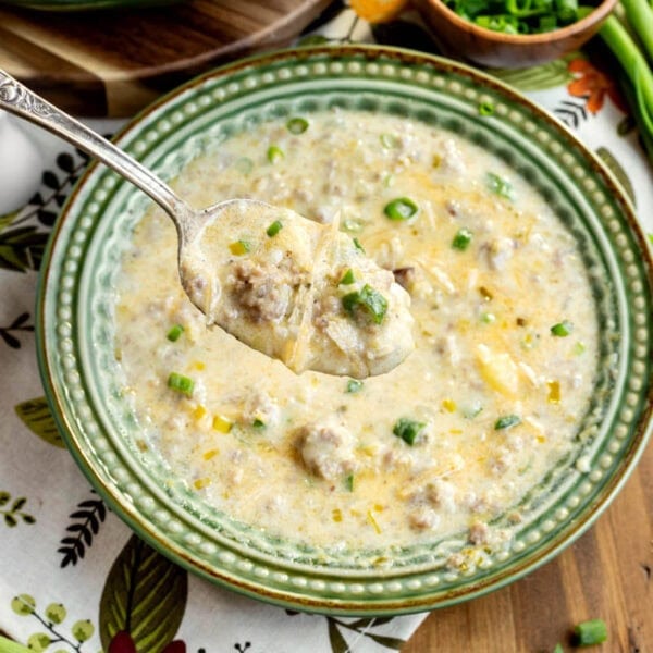 potato leek sausage soup in a green bowl with spoonful hovering above it.