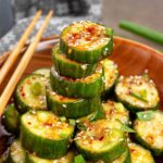 Asian cucumber salad in a wood bowl with chopsticks on the side