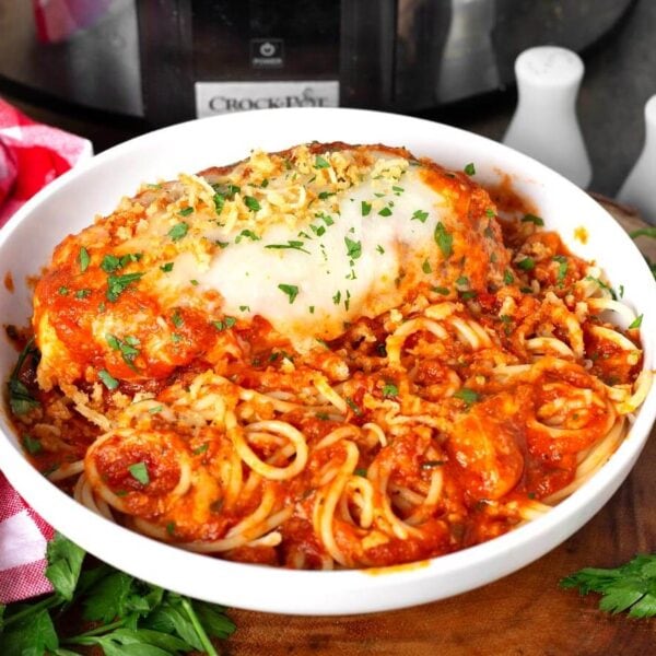 crockpot chicken parmesan in a white bowl with spaghetti