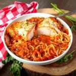 crockpot chicken parmesan in a white bowl with spaghetti