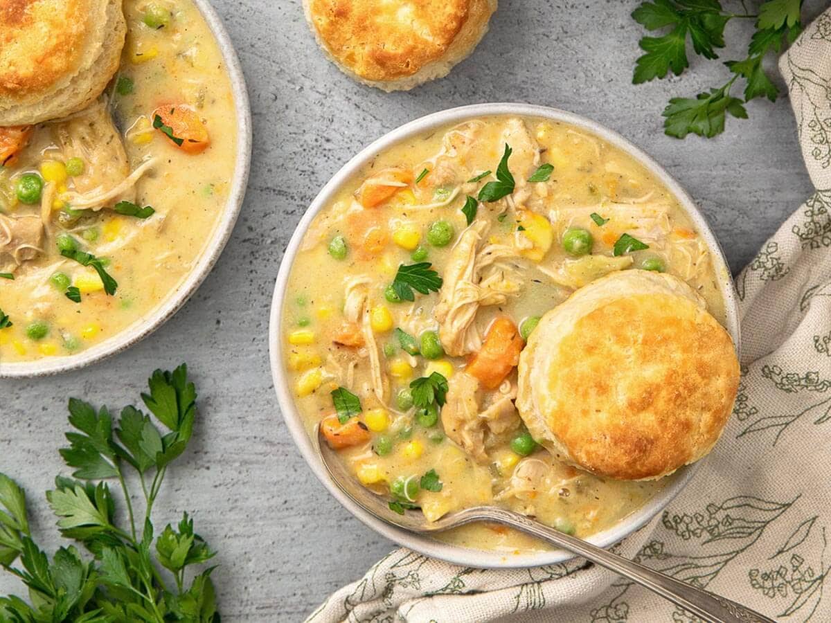 Overhead view of Instant Pot Chicken Pot Pie served in bowls with golden biscuits and chopped parsley