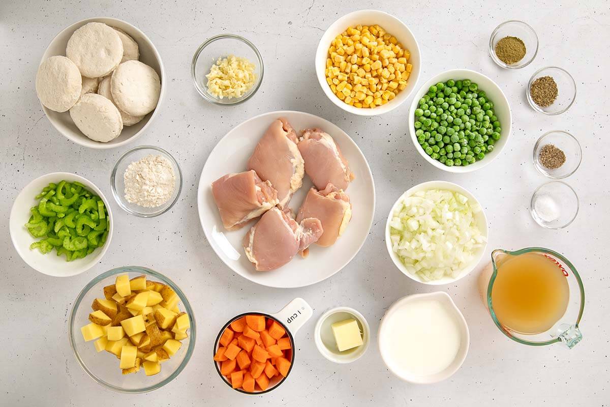 Ingredients for Instant Pot Chicken Pot Pie, including chicken thighs, vegetables, broth, milk, butter, flour, seasonings, and biscuits