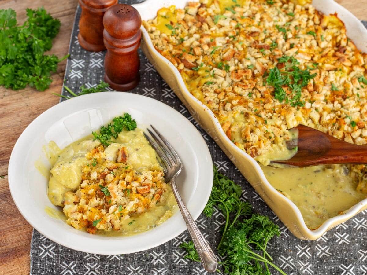 Chicken and stuffing casserole served on a white plate with the baking dish in the background
