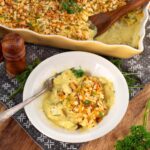 Chicken and stuffing casserole served on a white plate with the baking dish in the background