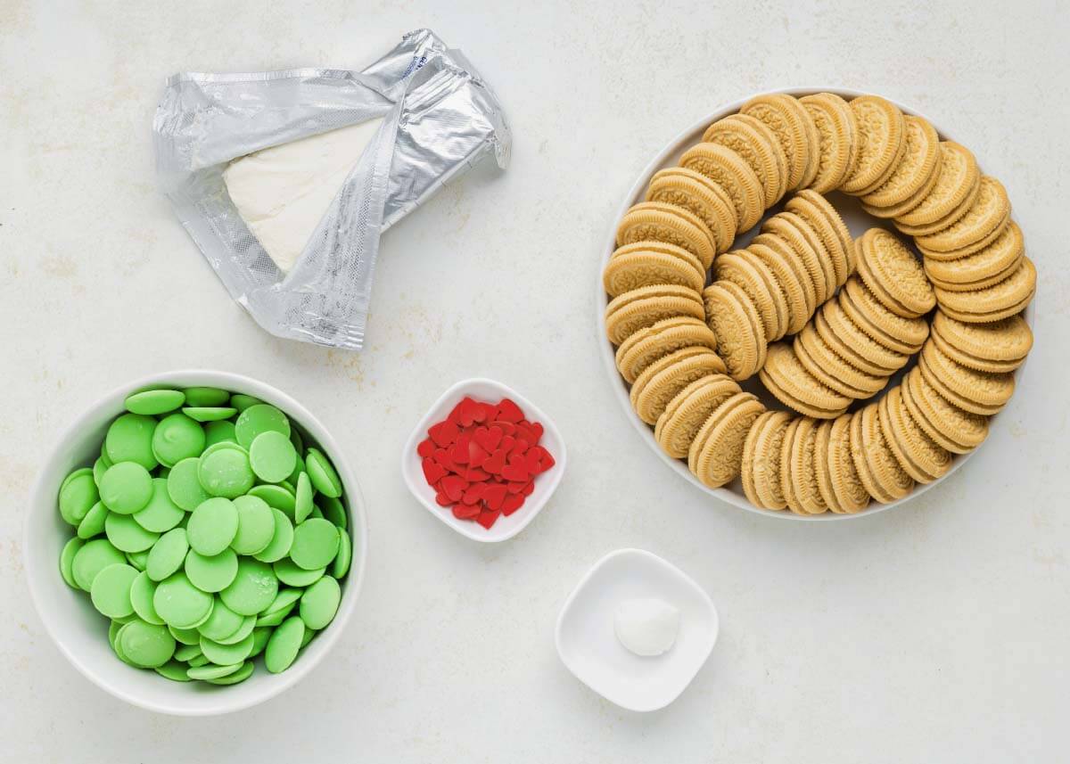 Golden Oreos, cream cheese, green candy melts, shortening, and red heart sprinkles for Grinch Truffles