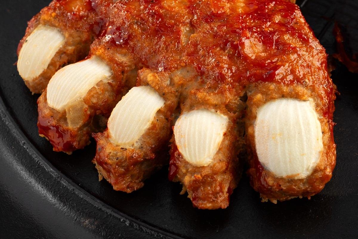 Close-up of Halloween meatloaf toes decorated with curved white onion toenails and a sweet ketchup glaze.