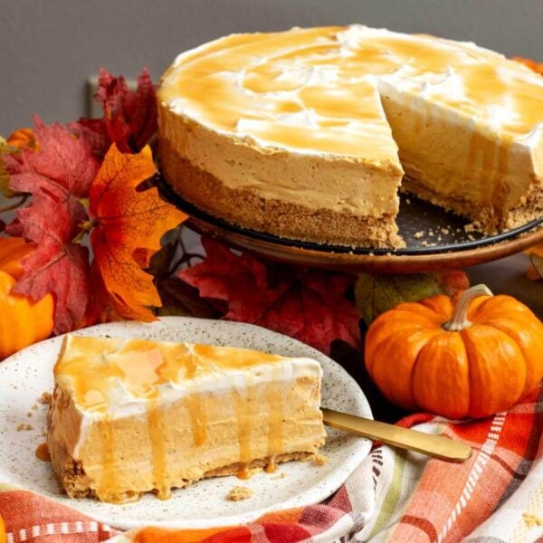 slice of No Bake Pumpkin Cheesecake on a plate with whole cheesecake with slice missing