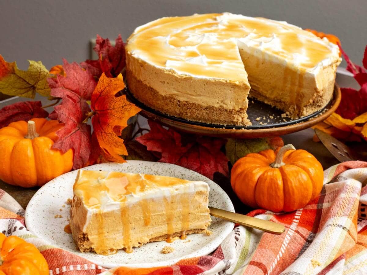 slice of No Bake Pumpkin Cheesecake on a plate with whole cheesecake with slice missing