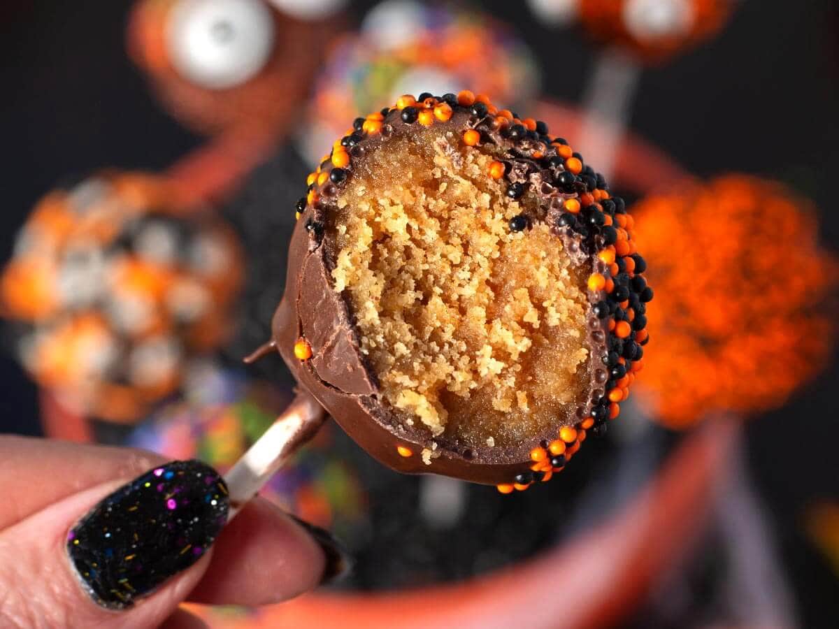 Bitten chocolate-covered Halloween cake pop showing the peanut butter cake filling inside