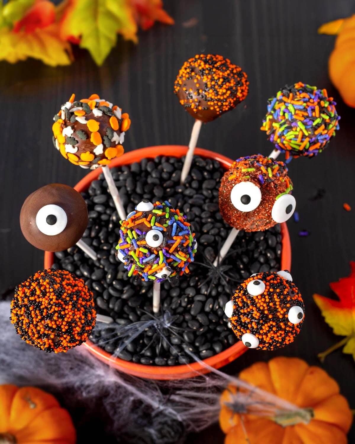Chocolate Halloween cake pops with colorful candy sprinkles and funny monster eyes