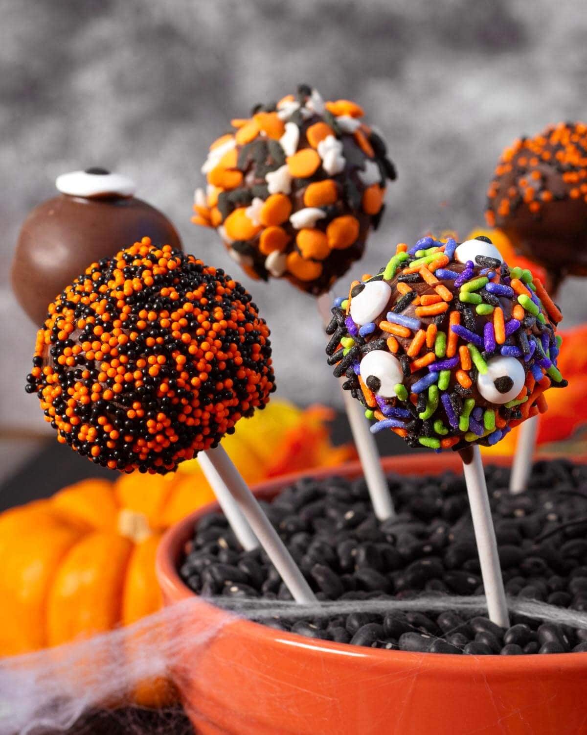 Chocolate Halloween cake pops with colorful candy sprinkles and funny monster eyes