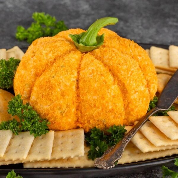 Pumpkin cheese ball and crackers on a black platter