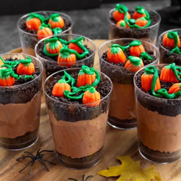Pumpkin Patch Dirt Cups with creamy chocolate pudding, Oreo cookie crumbs, candy pumpkins, and green icing vines