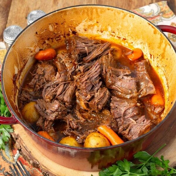 Tender shredded barbecue beef with potatoes and carrots in a red Dutch oven